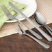 A Walco stainless steel dinner knife on a table with silverware.