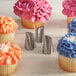 A cupcake with blue frosting and a flower design piped onto it using a silver Ateco Korean flower piping tip.