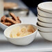 A close up of a Front of the House Kiln white porcelain bowl filled with vanilla sugar on a counter.