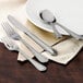 A Walco Accolade stainless steel dinner knife on a white plate with a spoon and fork.