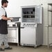 A man in a black apron standing in front of a Beverage-Air undercounter freezer.