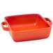 A red square ceramic baking dish with handles.