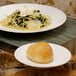 A white porcelain saucer with food on a table.