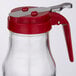 A Tablecraft glass syrup dispenser with a red lid.