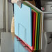 A person holding a stack of stainless steel cutting boards.