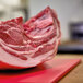 A piece of meat being cut on a Vollrath cutting board with a white background.