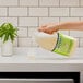 A person pouring Mrs. Meyer's Lemon Verbena Laundry Detergent into a plastic container.