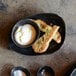 A black and white porcelain oval plate with food and a bowl of dip on it.