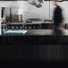 A man using a Vollrath blue cutting board on a counter in a professional kitchen.