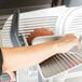 A person using a Centerline by Hobart meat slicer to slice meat on a counter.