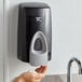 A person using a Rubbermaid manual foam soap dispenser.