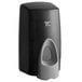 A black and grey Rubbermaid manual foam soap dispenser with a round hole and a handle.