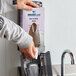 A person using a Rubbermaid black manual foam soap dispenser.