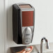 A person using a Rubbermaid Lumecel soap dispenser over a sink.