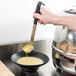 A person using a Vollrath Jacob's Pride stainless steel ladle to pour soup into a bowl.