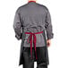 A man wearing a grey denim Uncommon Chef apron with red webbing.