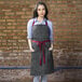 A woman wearing a Uncommon Chef pinstripe denim bib apron with burgundy webbing.