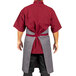 A man wearing a slate gray apron with burgundy accents.