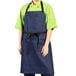 A woman wearing an indigo denim Uncommon Chef bib apron with black webbing.