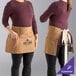 A woman wearing a brown Uncommon Chef waist apron with natural webbing and a logo.