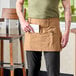 A man wearing a brown Uncommon Chef waist apron with natural webbing.