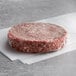 A raw Warrington Farm Meats burger patty on white paper.