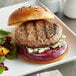 A Warrington Farm Meats ground chuck, short rib, and brisket burger with blue cheese, onions, and vegetables on a plate.