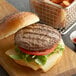 A Warrington Farm Meats ground chuck, short rib, and brisket burger patty on a cutting board with a burger bun on the side.