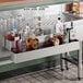 A 32-inch Steelton stainless steel double tier speed rail holding various liquor bottles behind a bar.