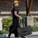 A woman walking with a large black Sterno food carrier bag.