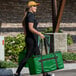 A woman carrying a large green Sterno food carrier bag.