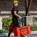 A woman carrying a red Sterno food carrier bag.