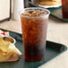 A plastic cup with a drink and a plate of chips.
