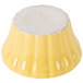 A yellow ramekin with a floral design on a yellow surface.
