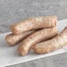 Three Warrington Farm Meats Weisswurst sausages on a white paper.