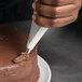 A person using a Matfer Bourgeat pastry bag to decorate a cake.