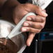 A person holding a Matfer Bourgeat nylon pastry bag over a bowl of chocolate.