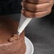 A person using a Matfer Bourgeat nylon pastry bag to decorate a cake.