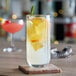 A Libbey highball glass filled with a lemon and rosemary cocktail on a table.