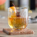 A Libbey rocks glass filled with liquid and a cherry.