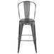 A Flash Furniture gray metal bar height stool with a vertical slat back and drain hole seat.