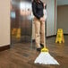 A woman holding a Rubbermaid disposable wet mop with a white headband.