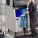 A woman filling an Avantco ice storage bin with a water bottle.