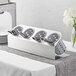 A Steril-Sil stainless steel flatware organizer with gray plastic cylinders holding silverware.