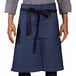 A man wearing a Uncommon Chef indigo denim apron with black webbing.