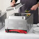 A man using an Avantco countertop food warmer to cook vegetables in a metal tray.