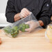 A person holding a LK Packaging plastic food bag of green bell peppers.