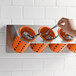 A hand holding a spoon in an orange Steril-Sil flatware container.
