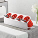 A Steril-Sil stainless steel flatware organizer with red perforated plastic cylinders holding silverware.