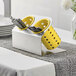 A Steril-Sil stainless steel flatware organizer with yellow perforated plastic cylinders holding silverware.